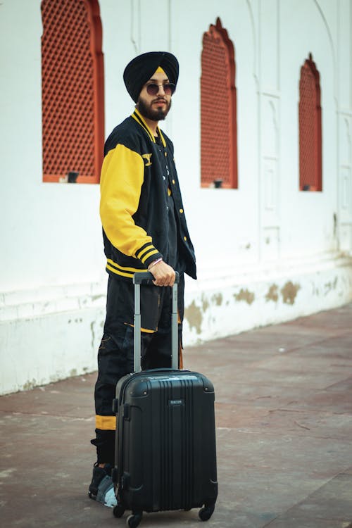 A man in yellow jacket and black pants with a suitcase