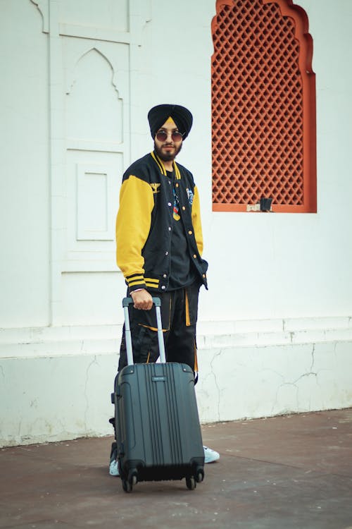 A man in a turban and jacket holding a suitcase