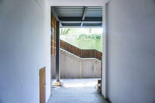 A bright, minimalist indoor hallway leading to a semi-outdoor staircase.