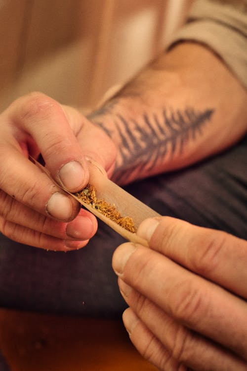A man with a tattoo on his hand holding a cigarette