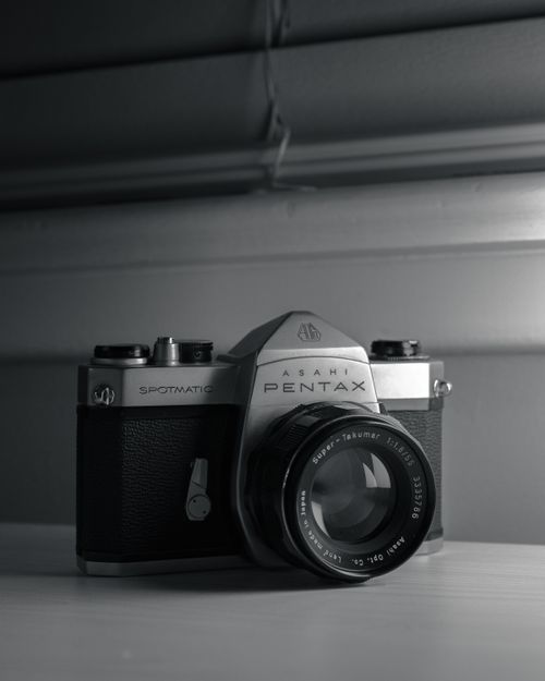 Free Black and white shot of a vintage Pentax 35mm camera showcasing classic retro design. Stock Photo