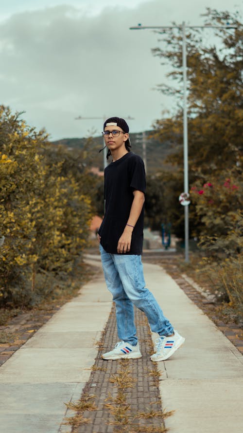 Man in T-shirt and Jeans Standing at Park