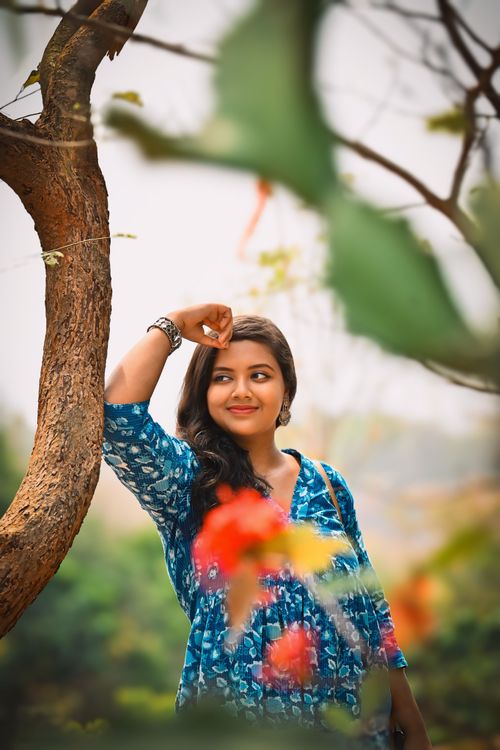 Free Charming woman in a blue dress smiling under a tree in Kolkata, India. Stock Photo