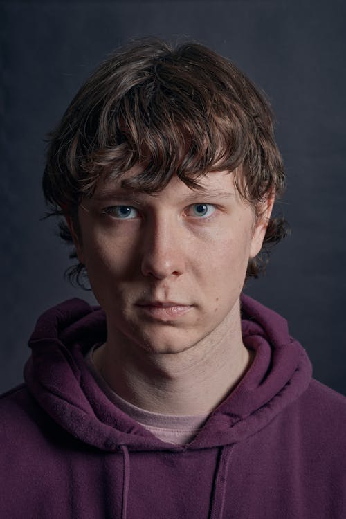A young man with blue eyes and a purple hoodie