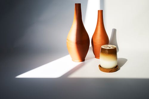 A candle and two vases sit on a table