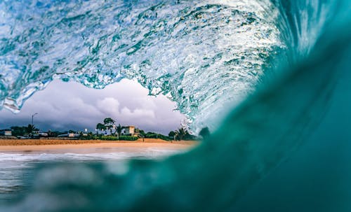 A wave breaking on the beach with a house in the background