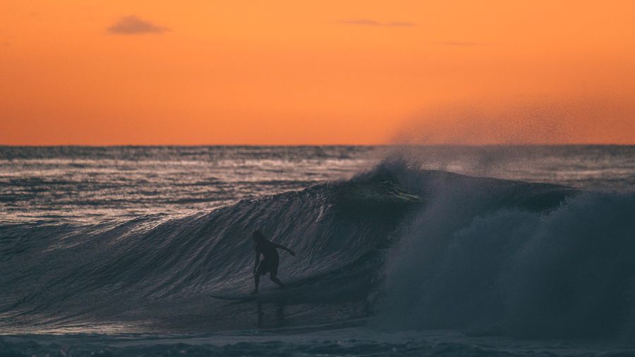 Silhouette of a surfer against a sunset sky by Dane Amacher on Pexels
