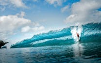 一个冲浪者在明亮的蓝天下冲浪，这个镜头充满了惊心动魄的感觉