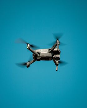 A modern drone flying against a clear blue sky, showcasing aviation technology.