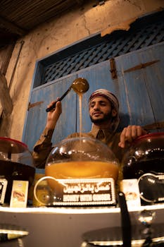 A vendor pouring honey in a traditional Dubai market, showcasing Middle Eastern culture.