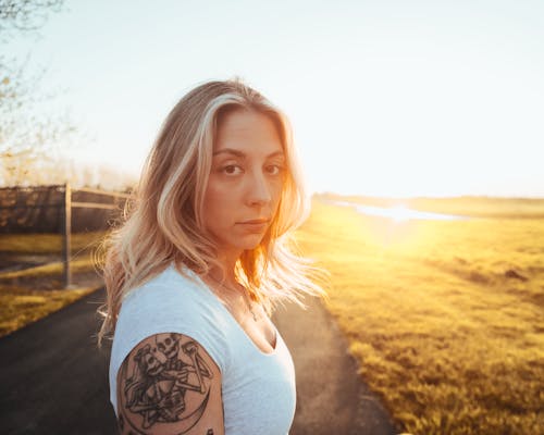 Free A woman with tattoos standing in front of a sunset Stock Photo