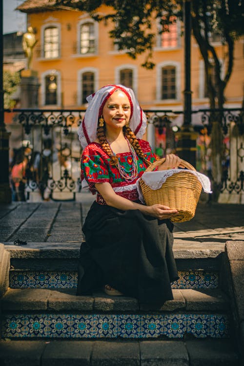 Free A woman in traditional clothing sitting on steps with basket Stock Photo