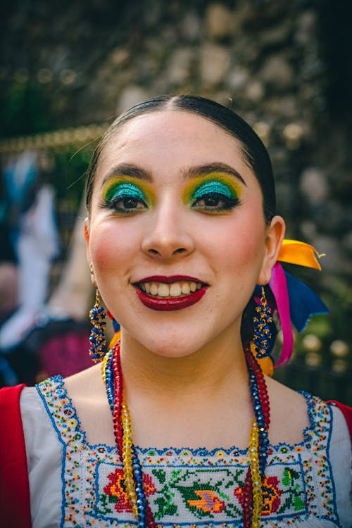 A woman with colorful makeup and colorful earrings