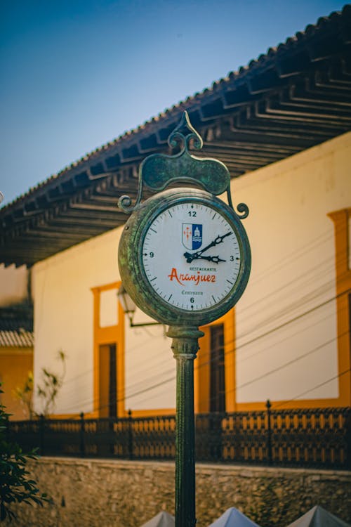 Free A clock on the side of a building with a white roof Stock Photo