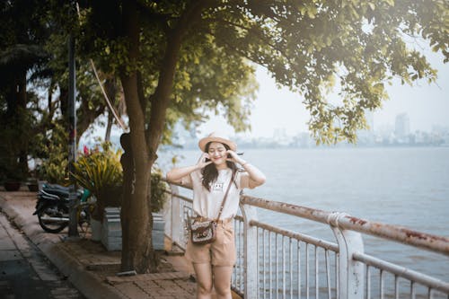 A woman in a hat and shorts standing on a bridge