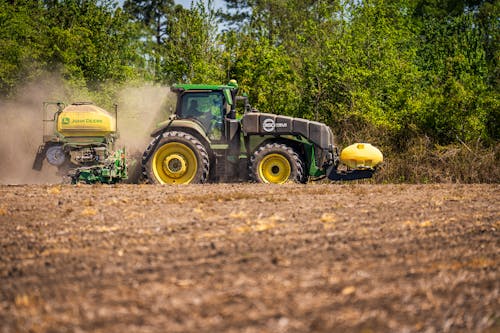 A tractor is spraying a field with fertilizer