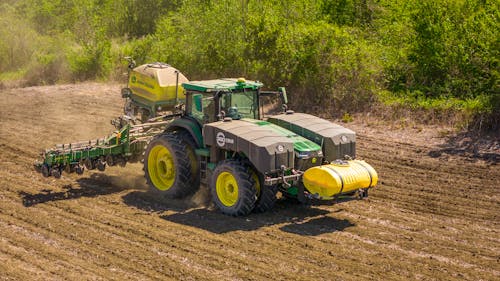 A Tractor with a Seeder on a Cropland 
