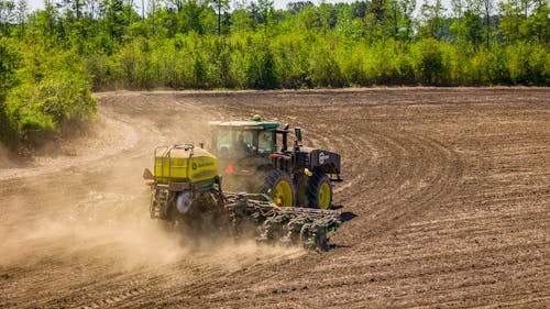A tractor is plowing the dirt in a field