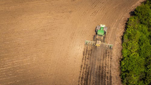 Drone Shot of a Tractor with a Seeder on a Cropland 