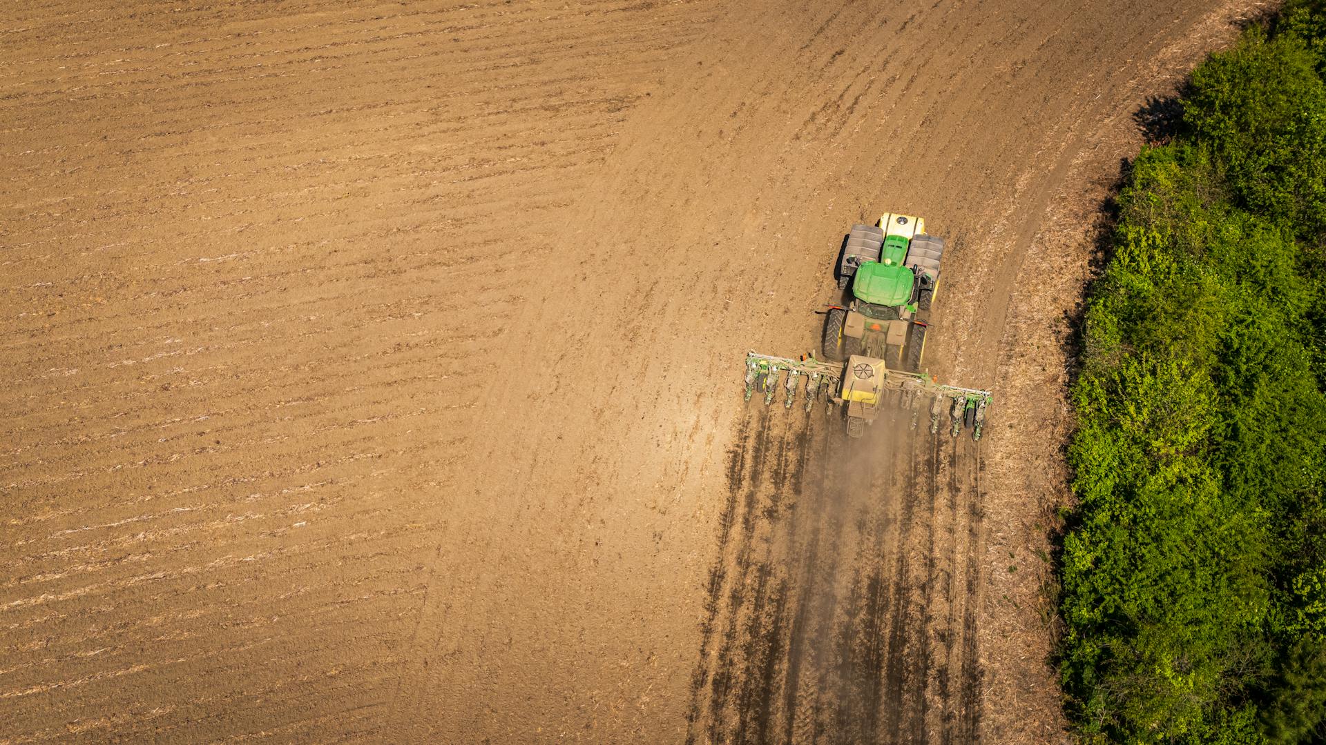 Drone Shot of a Tractor with a Seeder on a Cropland