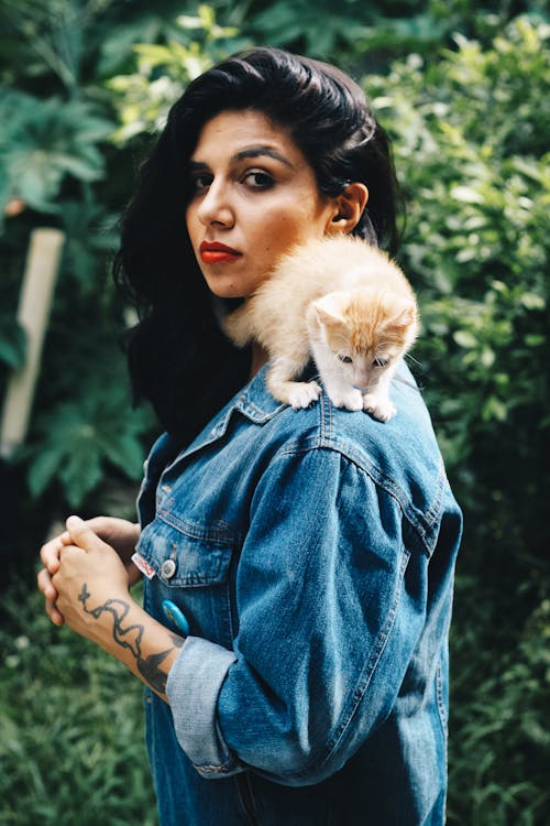 Standing Woman With Orange Tabby Kitten on Her Shoulder