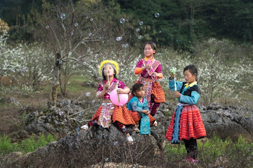 灰色の岩の近くの部族のドレスを着た4人の女の子