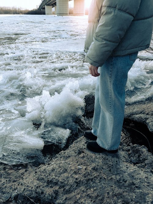 A person standing on the edge of a frozen river
