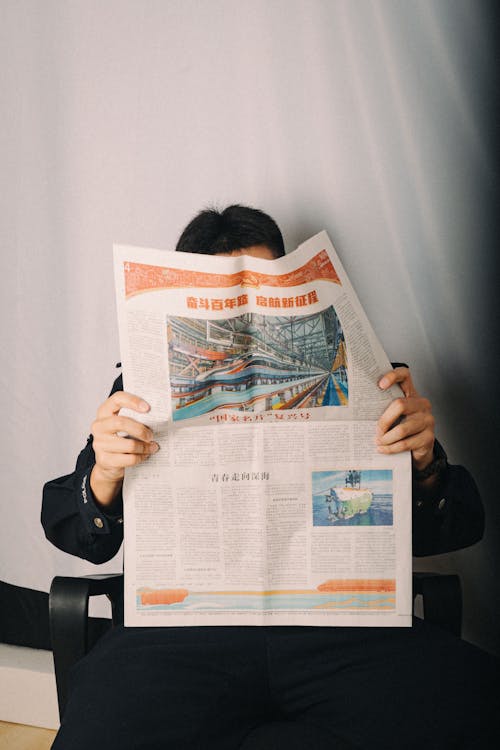A person sitting in a chair with a newspaper in front of them