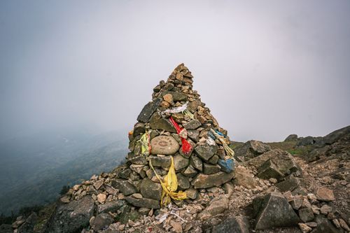 Free A pile of rocks adorned with colorful prayer flags on a foggy mountain offers a serene travel experience. Stock Photo