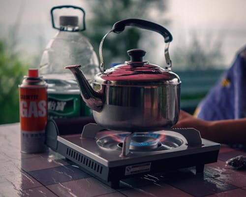 A kettle on a stove with a bottle of water