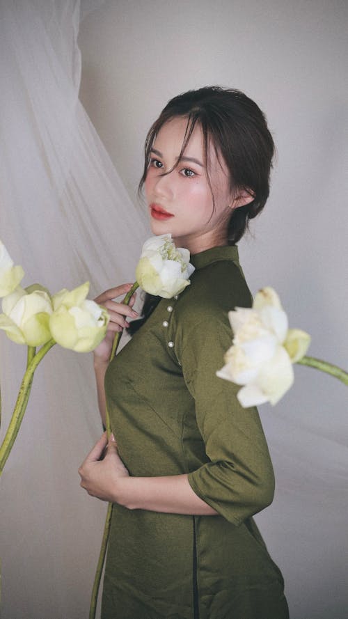 Free A woman in a green dress holding white flowers Stock Photo