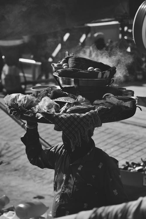 Free A black and white photo of a man carrying a tray of food Stock Photo