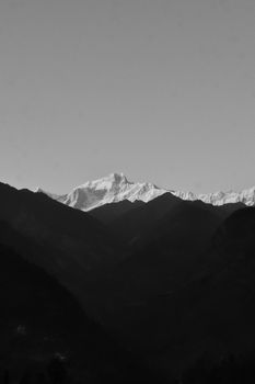 A stunning black and white view of a snowy mountain range under a clear sky.