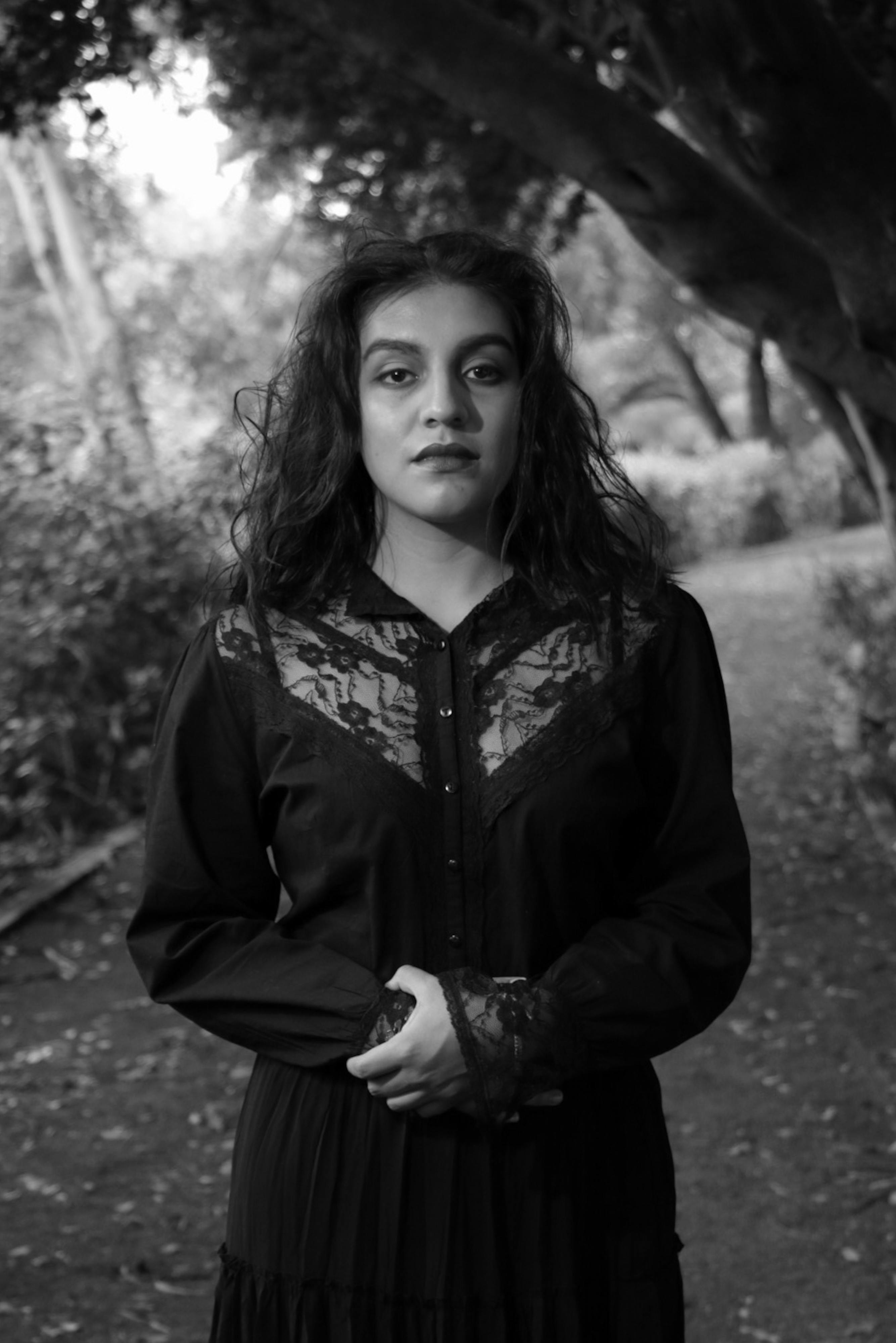 Black and white portrait of a woman standing outdoors, exuding elegance and grace.