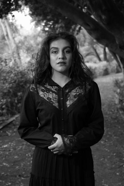 Black and white portrait of a woman standing outdoors, exuding elegance and grace.