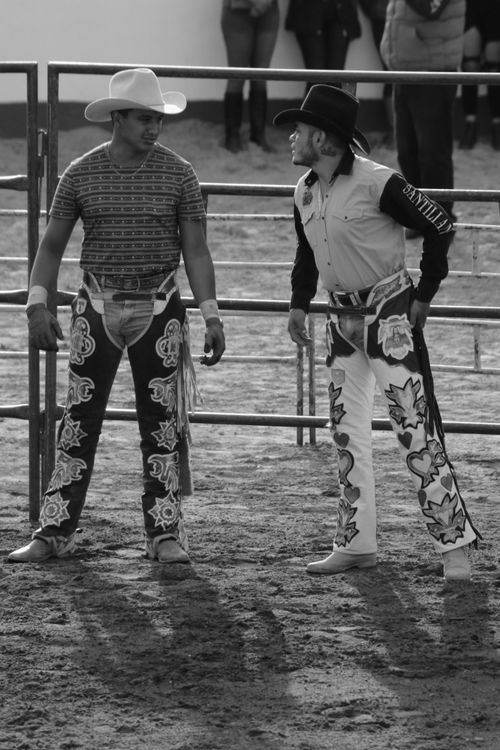Free Two cowboys in decorative attire engage at a rodeo event, captured in black and white. Stock Photo