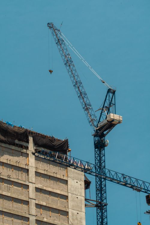 Free View of a construction crane against a clear blue sky in Mexico City, capturing urban development. Stock Photo