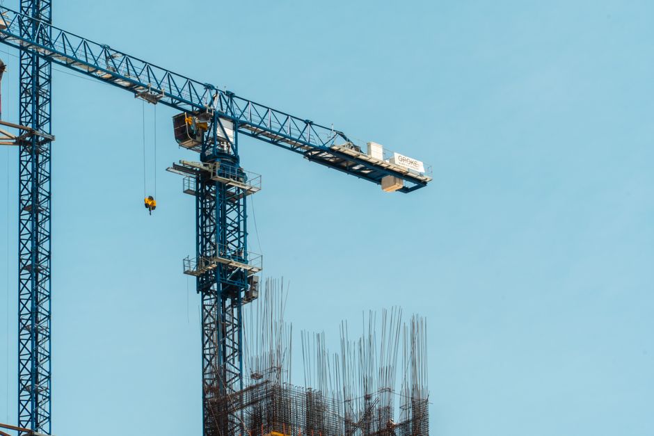 A tall tower crane at a construction site amidst a clear blue sky, in Mexico City.