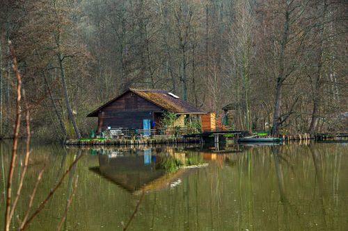 Free Serene cabin reflecting on a calm lake in Lauda-Königshofen, Germany. Ideal for nature lovers. Stock Photo