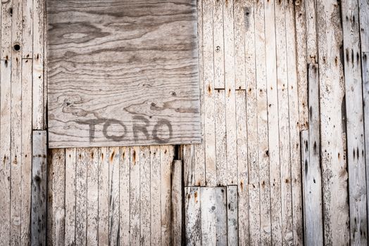 Aged wooden wall with rustic texture and 'TORO' graffiti in Tabernas, Spain.