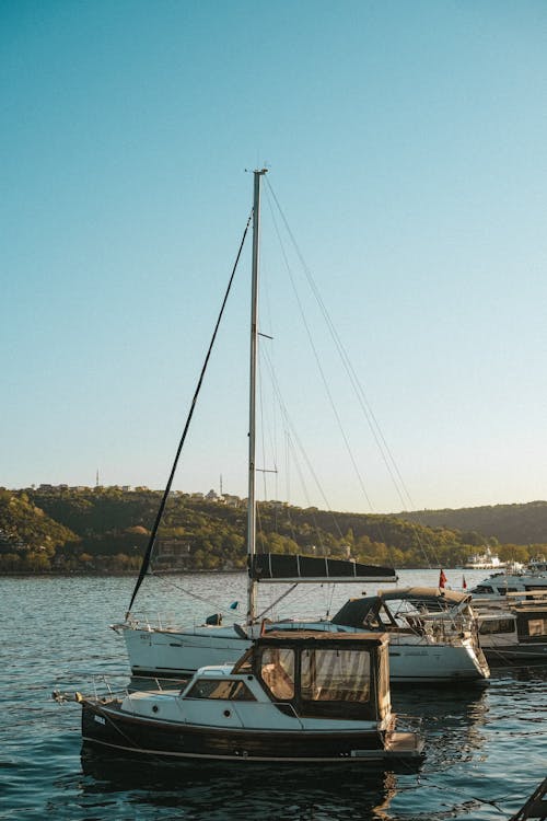 A boat docked at a dock with a sailboat