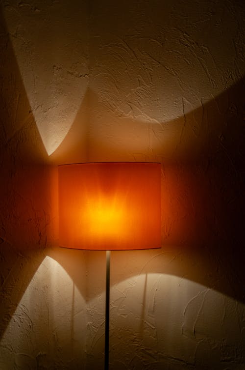 A lamp with a orange shade on a wall