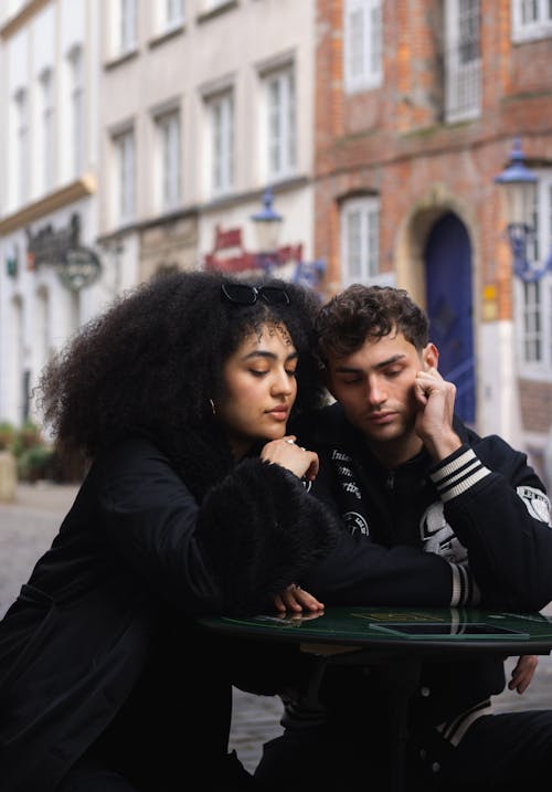 A man and woman sitting at a table in front of a building