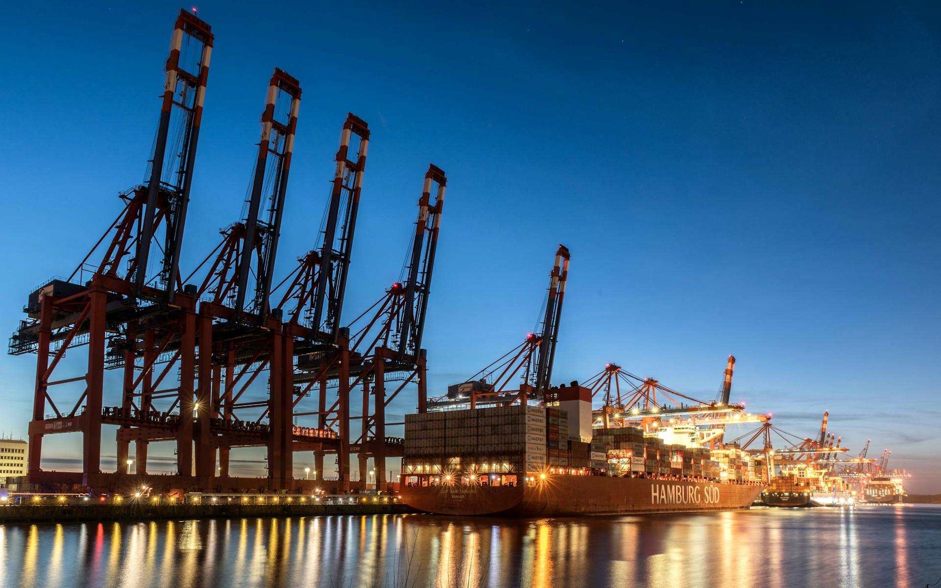 A night view of cargo cranes and a container ship at Hamburg harbor, Germany.