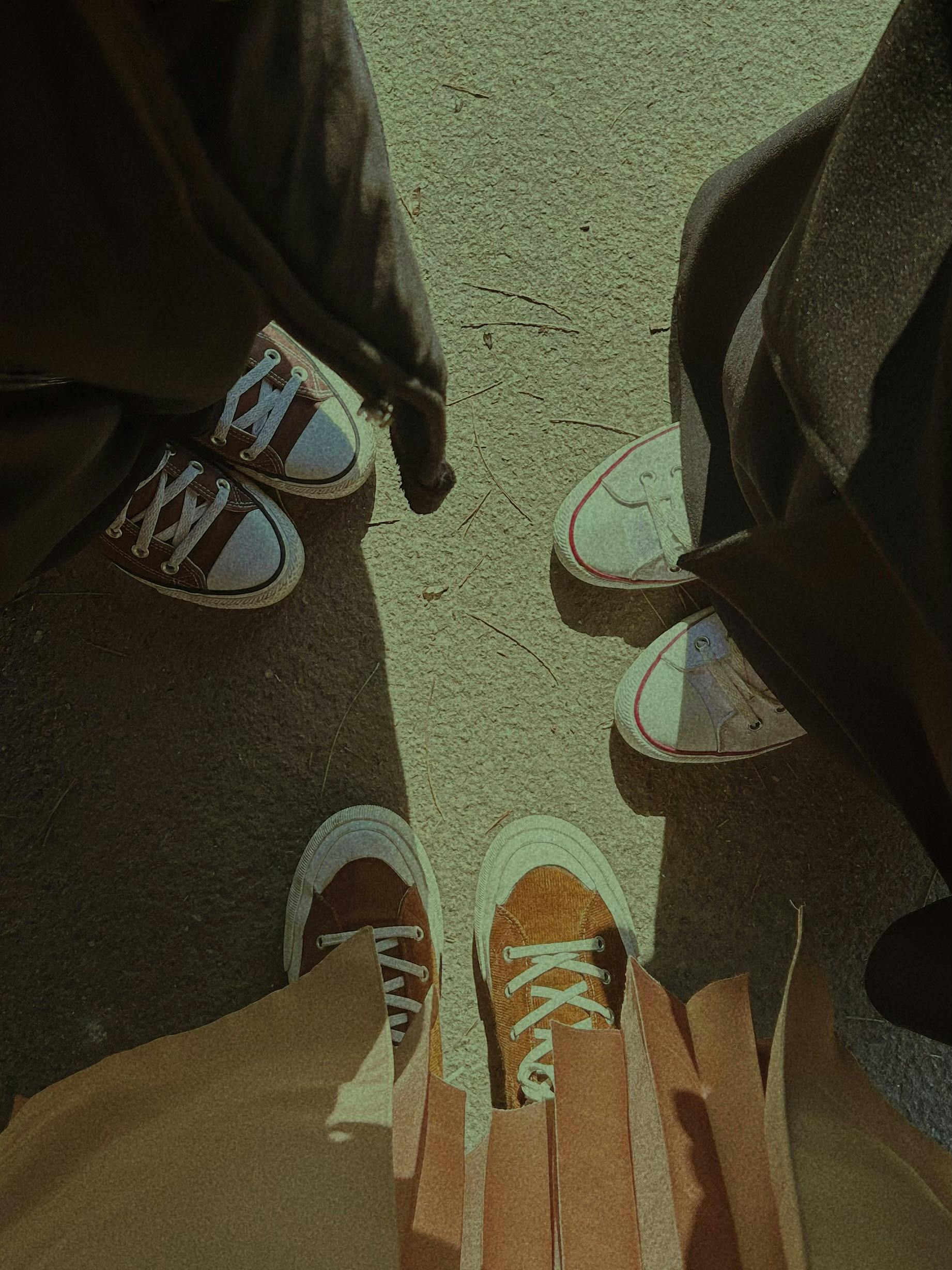 Three pairs of sneakers in a casual urban setting, seen from above.