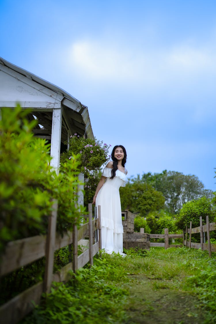 Beautiful Brunette Woman In White Dress Posing In Garden