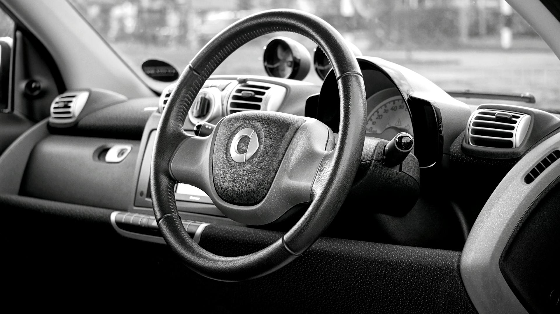 Black and white photo of a smart car interior showcasing a modern dashboard and steering wheel.