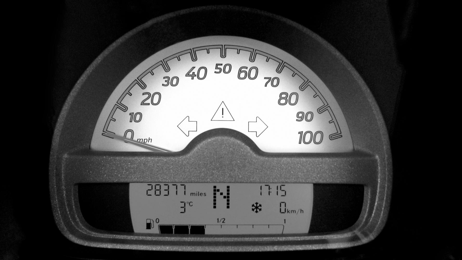 Black and white photograph of a car's speedometer and odometer showing 28377 miles and gear in neutral.