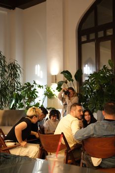 A group of people sharing ideas in a stylish indoor space with natural plants.