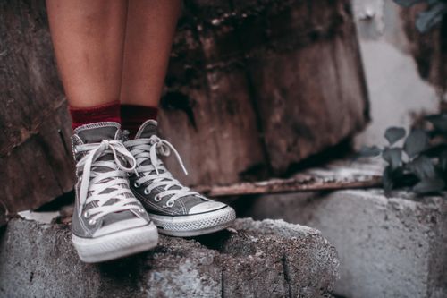 Free Close-up of gray high-top sneakers with red socks on textured concrete, outdoor fashion statement. Stock Photo